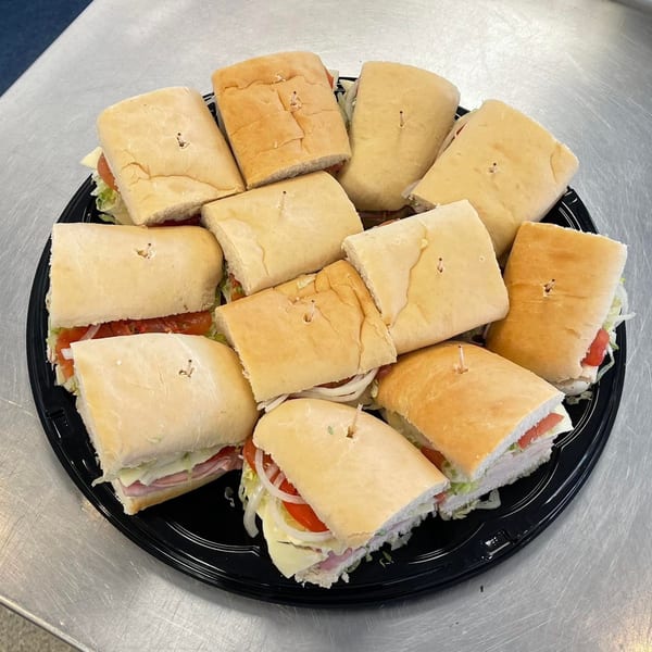 A catering platter of Big's Pizza and Subs' assorted subs, cut in half, with toothpicks.