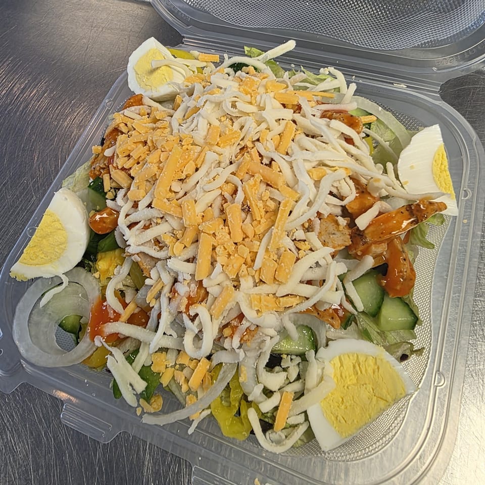 A Big's Pizza and Subs chef salad with chicken, cheese, hard-boiled eggs, and vegetables in a plastic container.