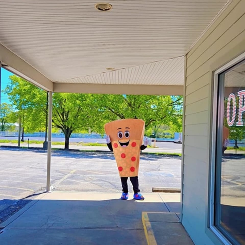 A person in a Big's Pizza slice mascot costume stands under an awning outside the restaurant.